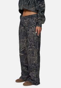 Camo-gepatroneerde, losse sweatpants in donkere grijstinten met een elastische tailleband en zijzakken. Zacht, textuurend stof.