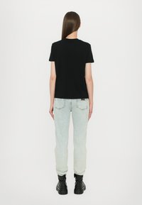 Svart kortermet t-skjorte kombinert med lyseblå denimbukser, med en innsvingt passform og svarte ankelstøvler. Enkelt design, ingen synlige mønstre.