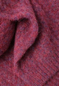 Rood en paars gestructureerd textiel met een zachte, pluizige afwerking en een geweven patroon. Het materiaal lijkt dik en warm.