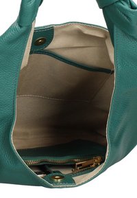 Teal leren handtas interieur met beige stofvoering, binnenzak met rits en gouden rits, en drukknopsluiting detail.