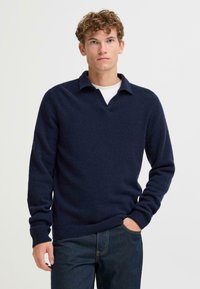 Marineblauwe gebreide pullover met V-hals en kraag, met lange mouwen en geribde boorden en zoom. Zachte textuur, casual ontwerp.