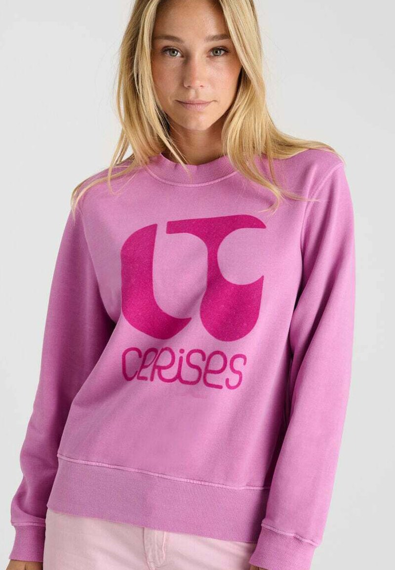 Sweatshirt rose en tissu doux, arborant un grand logo contrasté en rose foncé avec des lettres stylisées "CC" et "cerises."
