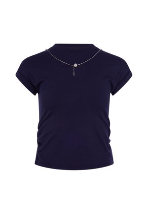 Camicia aderente blu navy a maniche corte con lati arricciati e una sottile collana d'argento con una singola perla e un ciondolo pendente.