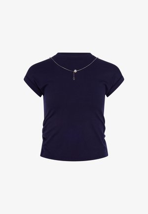 Navy blue short-sleeve fitted shirt with ruched sides and a thin silver necklace featuring a single pearl and dangling charm.