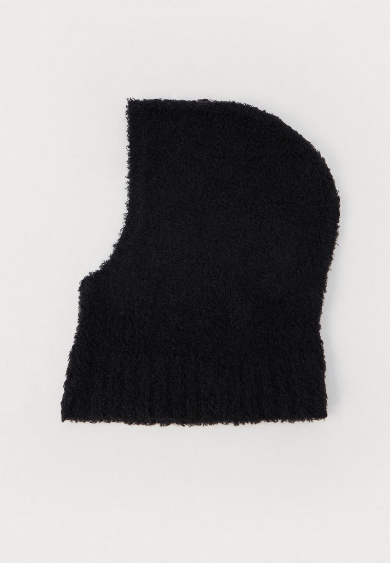 Melnā adīta beanie cepure, izgatavota no mīksta, teksturēta materiāla. Piemērota apaļai formai ar ribotu maliņu apakšā, paredzēta siltumam.