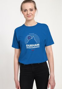 Niebieska bawełniana koszulka z grafiką górską, przedstawiającą linie i okrągły akcent. Napis "DURHAM MOUNTAINEERING" wytłuszczonym białym drukiem.