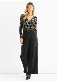 Leopard print long-sleeve top with a deep V-neck, paired with high-waisted, wide-leg black denim pants and black heeled ankle boots.