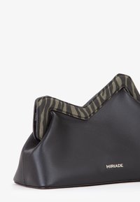Borsa nera sintetica con una patta a zigzag di colore verde, caratterizzata da una texture liscia e un piccolo logo sul lato.