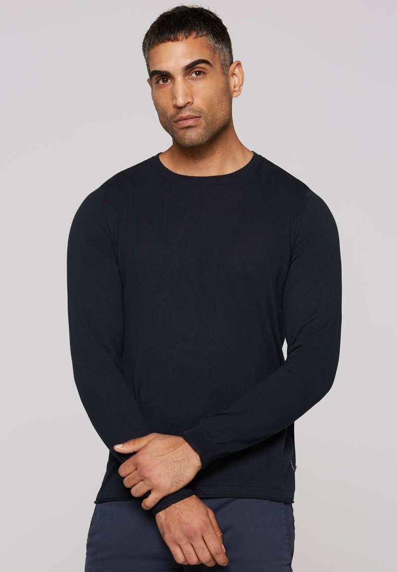 Black long-sleeve shirt made of soft fabric; features a round neckline, slim fit, and ribbed cuffs, with subtle side detailing.