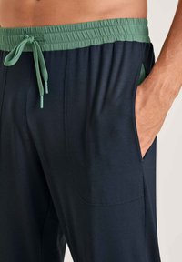 Navy joggings met een groene elastische tailleband en trekkoord. Voorzien van zijzakken en een zachte stofstructuur.