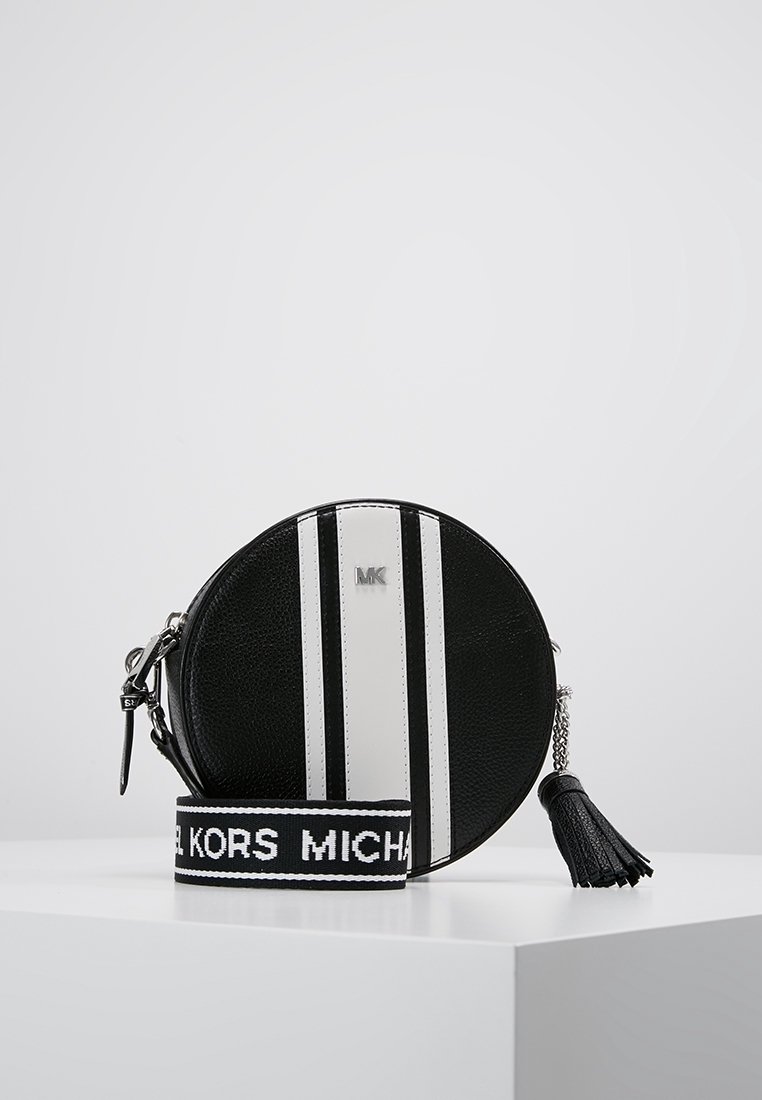 Borsa circolare in pelle nera con strisce verticali bianche, con logo "MK" in cima. Presenta una tracolla removibile e un accento a frange.