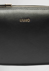 Portefeuille en cuir noir avec une surface texturée, logo doré "LIU JO" et détails de fermeture éclair dorée. Design épuré sans embellissements supplémentaires.