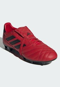 Scarpa da calcio rossa in pelle con accenti neri, caratterizzata da un design trapuntato e una parte anteriore con lacci. Suola dotata di tacchetti per una migliore aderenza.