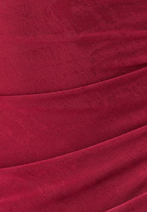 Primo piano di tessuto rosso a strati con una fine trama diagonale a coste e pieghe morbide che creano linee curve.