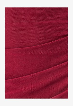 Close-up of layered red fabric with fine diagonal ribbed texture and soft folds creating curved lines.