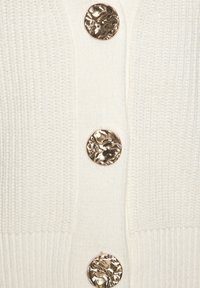 Weißer Strickcardigan mit vier runden, goldfarbenen Dekorationsknöpfen mit strukturiertem Design auf der Vorderseite. Weicher Stoff mit geripptem Saum.