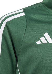 Zelena sportska majica od teksturiranog materijala, s bijelim prugama na ramenima i adidas logom na prsima.