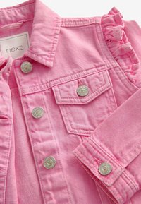 Rosa Jeansjacke mit silbernen Druckknöpfen, Brusttasche und Rüschendetails an den Schultern. Weicher Stoff mit vertikalen Streifen.