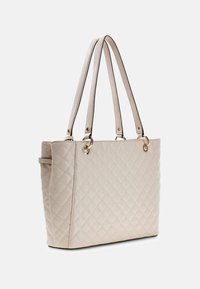Borsa a tote trapuntata beige con manici doppi, accentuata da elementi in oro e bordi neri. Presenta una forma rettangolare strutturata e una superficie texturizzata.