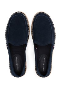 Zapatos de ante azul marino tipo slip-on con suela de yute, que presentan costuras de contraste y un interior textil negro. Logotipo impreso en las plantillas.