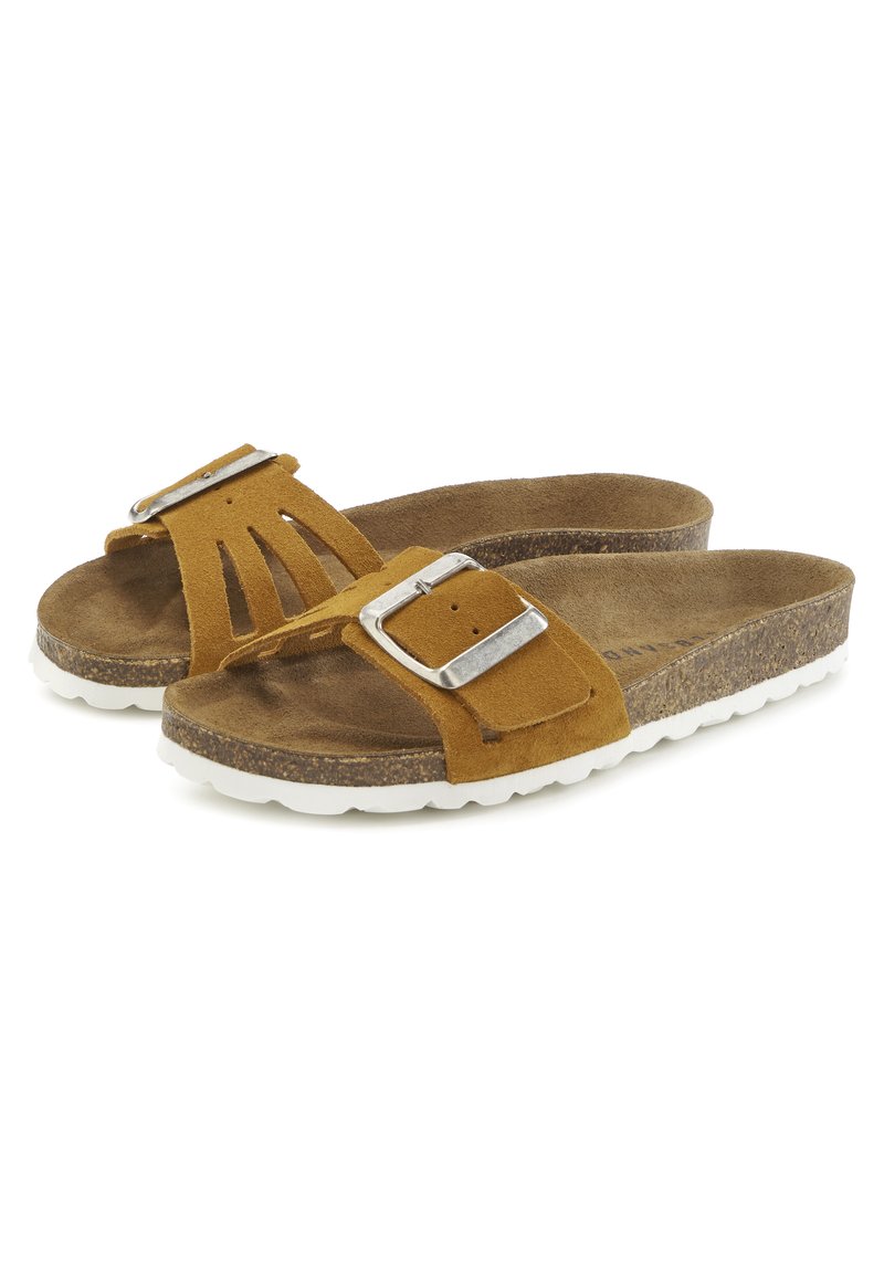 Sandales en daim marron avec une large bride présentant des découpes et une boucle en métal argenté. Semelle en liège avec une semelle extérieure en caoutchouc blanc pour une meilleure adhérence.