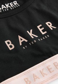 Crna tkanina košulja s velikim, metalik ružičastim natpisom "BAKER" i teksturiranim remenom ispod. Oznaka: "by TED BAKER".
