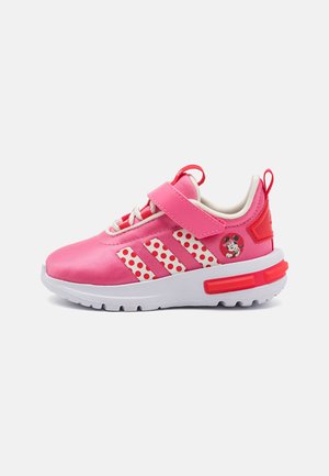 Pink children's sneakers with a fabric upper, white polka-dot accents, Velcro strap, and a small character graphic on the side. White sole.
