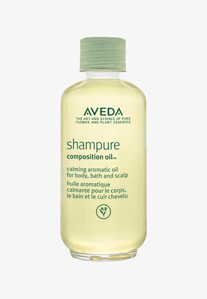 Bouteille en plastique transparent avec un capuchon vert, contenant de l'huile aromatique calmante jaune ; étiquetée pour une utilisation sur le corps, dans le bain et sur le cuir chevelu, de la marque AVEDA.