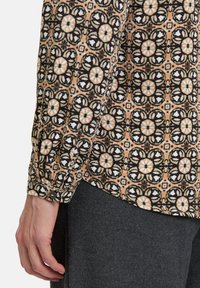 Musterhemd mit langen Ärmeln in Beige, Schwarz und Weiß mit floralem Design; verfügt über eine Knopfmanschette und einen strukturierten Stoff mit glatter Oberfl�äche.