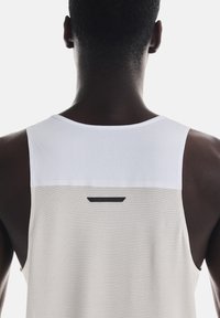 Hvid ærmeløs atletisk tanktop med et struktureret mesh-design, der har en sort aksent nær halsen og et glat bagpanel.