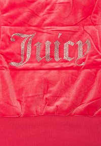 Top in velluto rosso con la parola "Juicy" in strass, caratterizzato da una texture arricciata e da un bordo a coste sull'orlo.