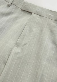 Pantaloni grigi chiari plissettati realizzati in tessuto texturizzato, con un sottile motivo a righe e una vita strutturata.