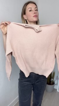 Suéter de malha rosa claro com textura canelada, mangas longas e decote arredondado. Apresenta uma bainha curva e um corte solto.