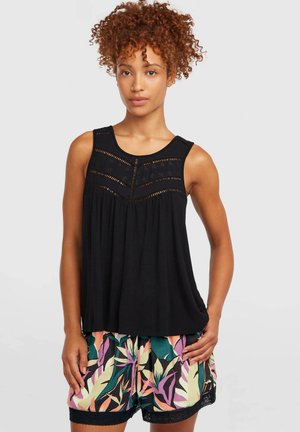 Čierny top bez rukávov s textúrovaným panelovým dizajnom a háčkovanými detailmi, v kombinácii s viacfarebnými šortkami s kvetinovou potlačou a čipkovým lemom.