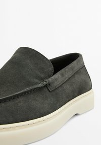 Graue Wildleder-Slipper mit abgerundetem Zeh, weißer Gummisohle und minimalistischem Stichdetail entlang der oberen Kante.