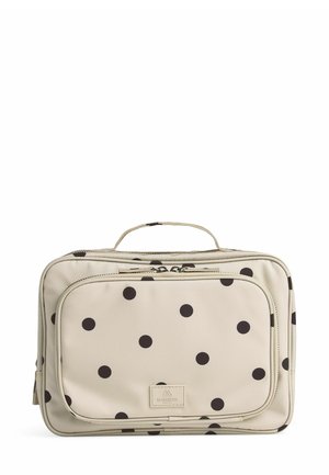 Sac beige à pois en tissu, avec des motifs circulaires noirs, une poignée supérieure et une poche zippée à l'avant avec une étiquette de marque.