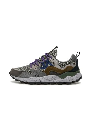 Sneaker multicolore con una tomaia a motivo grigio e nero, accenti marroni e verdi, lacci viola e una suola grigia maculata.