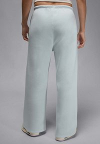 Jasnoniebieskie szerokie spodnie dresowe o miękkiej tkaninie, elastycznym pasie i ściągaczach, z gładką teksturą.