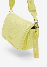 Borsa gialla con texture, design a fiore modellato, tracolla regolabile e un'etichetta con la scritta "I ♥ Desigual" in caratteri bianchi.