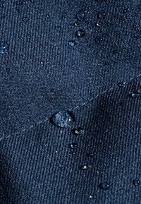 Waterafstotende marineblauwe stof met een gestructureerd oppervlak, met druppels water erop die de vochtafstotende eigenschappen benadrukken.