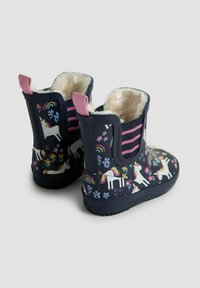 Bottes de pluie en caoutchouc de couleur marine avec des motifs colorés de licornes et de fleurs, des accents roses et une doublure en fourrure. Elles possèdent une semelle texturée et des poignées de traction.