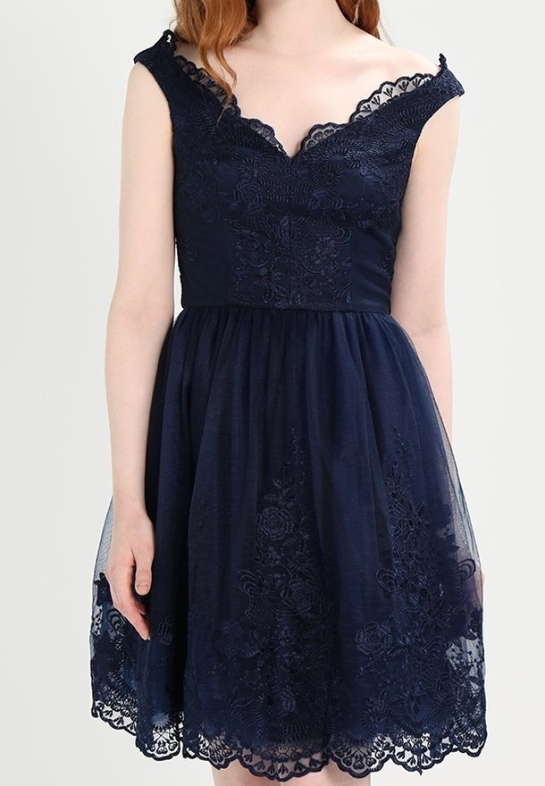 Navy blue dress with a fitted bodice, lace trim, and floral embroidery. Skirt is layered tulle with scalloped lace hem. Sleeveless design.