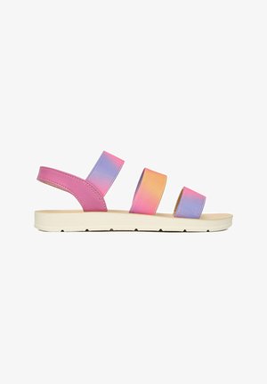 Sandale plată cu talpă albă și trei bretele gradient în violet, roz și portocaliu, plus o curea roz pentru gleznă pe fundal alb.