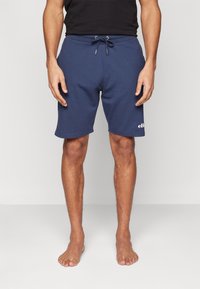 Marineblauwe shorts van zacht materiaal, met een elastische tailleband en trekkoord, en een bedrukt logo op de linkerzoom. Casual, knielang ontwerp.