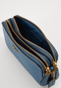 Blue textured leather wallet with gold hardware, featuring two zippered compartments and a smooth interior lining.