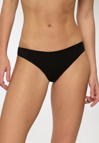 Slip in cotone nero con taglio a vita bassa, texture liscia e fascia elastica in vita. Design semplice senza motivi o decorazioni.