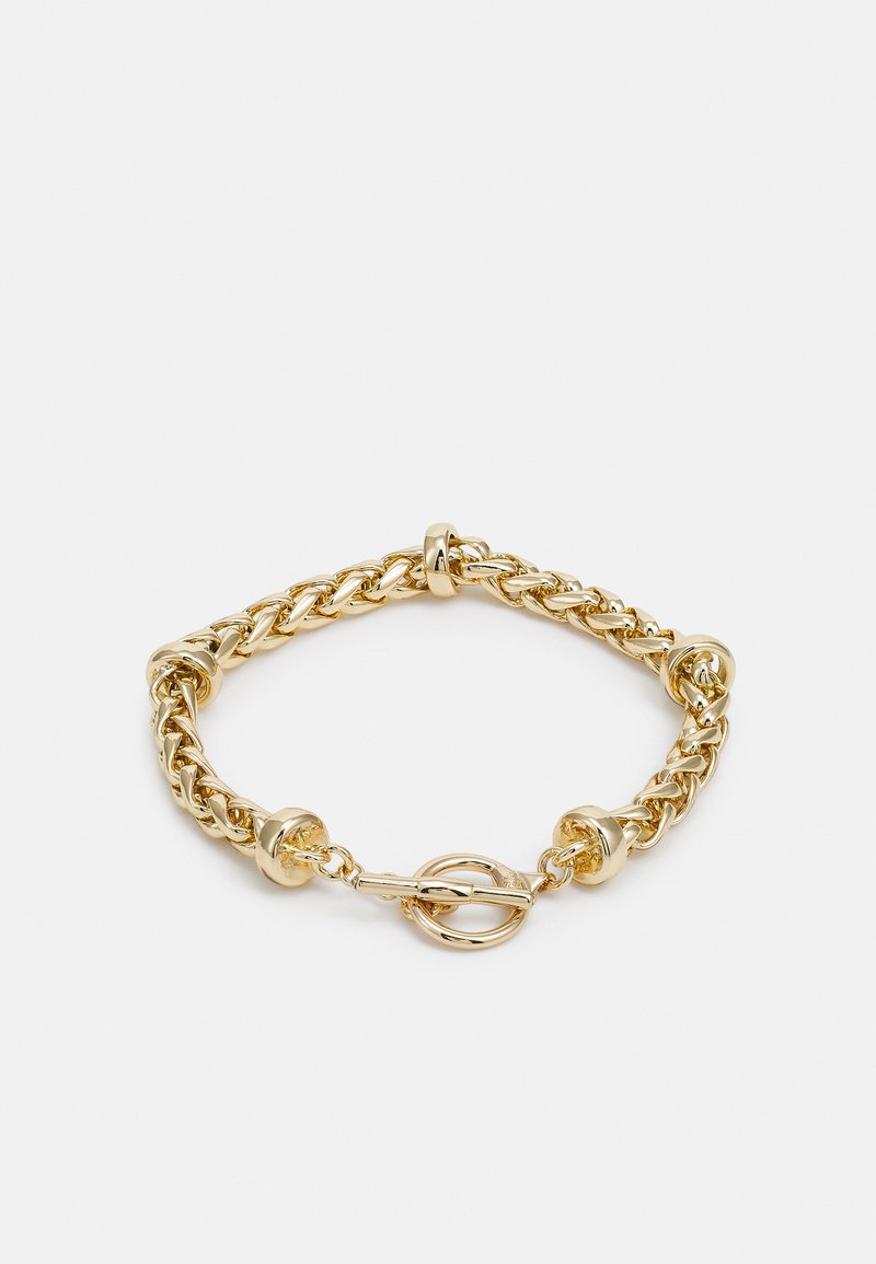 Bracelet en chaîne dorée avec des maillons entrelacés, des accents métalliques ronds et un fermoir à bascule. Fini lisse et brillant avec une texture métallique.