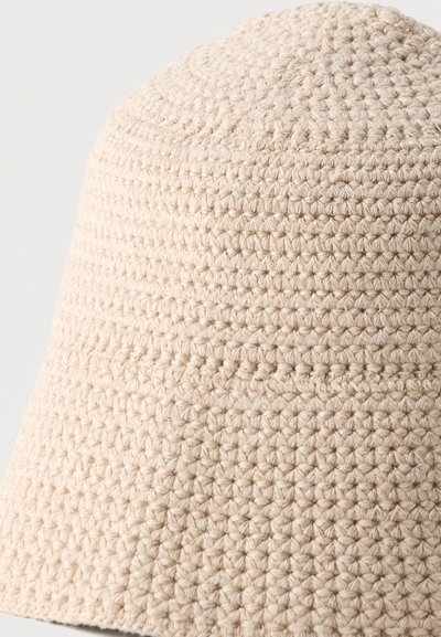 Μπεζ καπέλο κάδου πλεκτό με υφή, στενό πλεκτό σχέδιο και απαλό, στρογγυλεμένο γείσο.