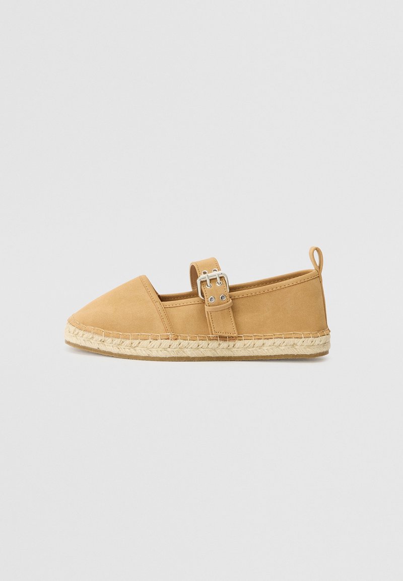 Tan nahka espadrille, jossa on terävä kärki, säädettävä solkiremmi ja juuttiköysi-pohja. Tasainen rakenne, rento muotoilu ja minimaaliset yksityiskohdat.