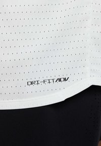 Λευκό αθλητικό μπλουζάκι με μικρές μαύρες οπές, με λογότυπο DRI-FIT ADV σε μαύρο στο τελείωμα. Λεία υφή, στρογγυλή λαιμόκοψη, κοντά μανίκια.